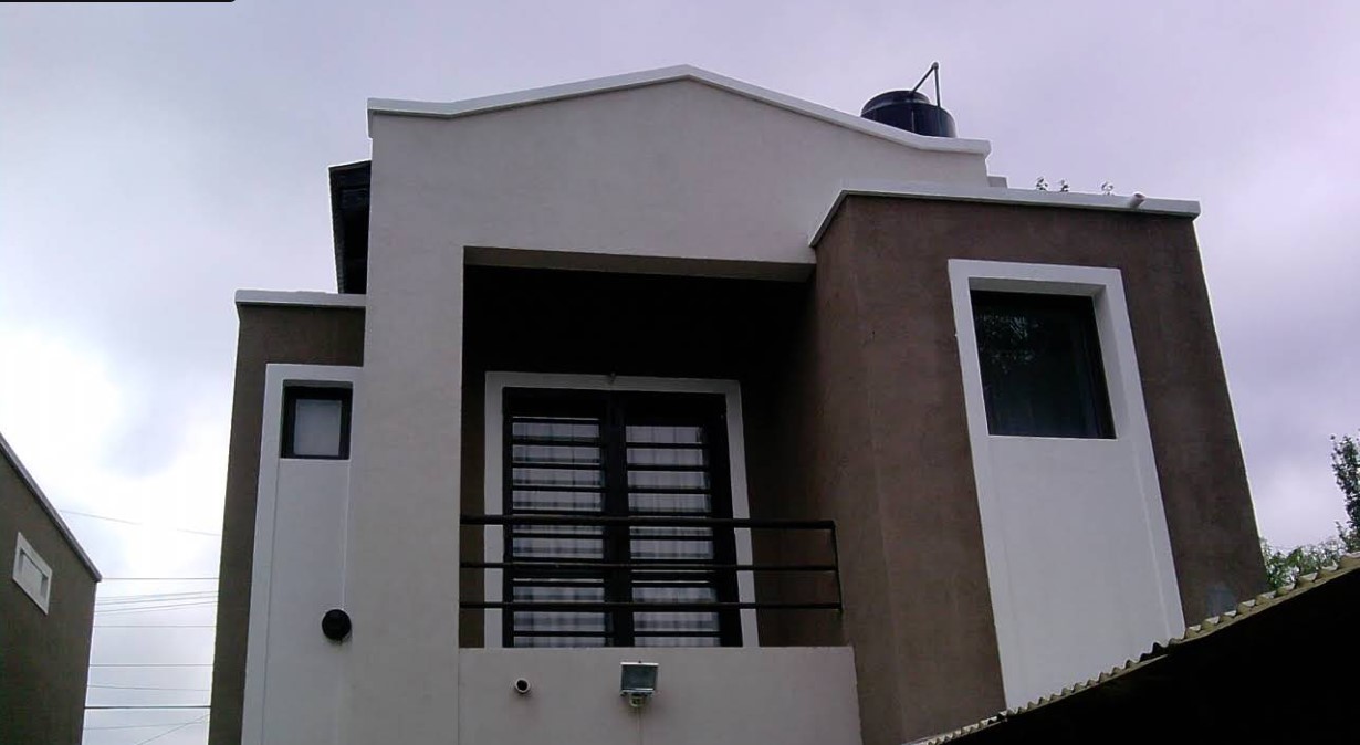 Frente de vivienda con balcón y terminaciones en tonos claros